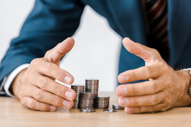 businessman grabbing silver coins at wooden table - Photo, Image