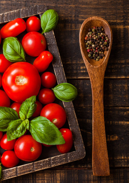 Organic Tomatoes with basil and pepper on spoon in vintage wooden box on wooden table - Foto, Imagem