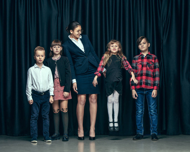 Cute stylish children on dark studio background. The beautiful teen girls and boy standing together - Fotografie, Obrázek
