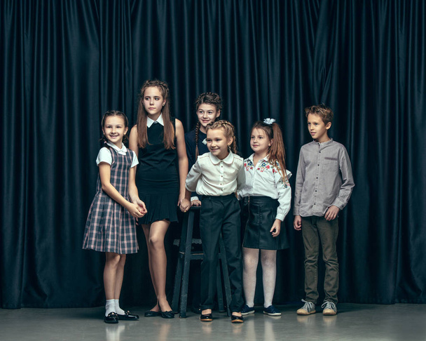 Cute stylish children on dark studio background. The beautiful teen girls and boy standing together - Foto, Imagem