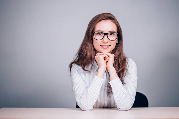 Teacher or business woman with glasses sitting at table and smiling at the camera, on white background - Foto, Bild