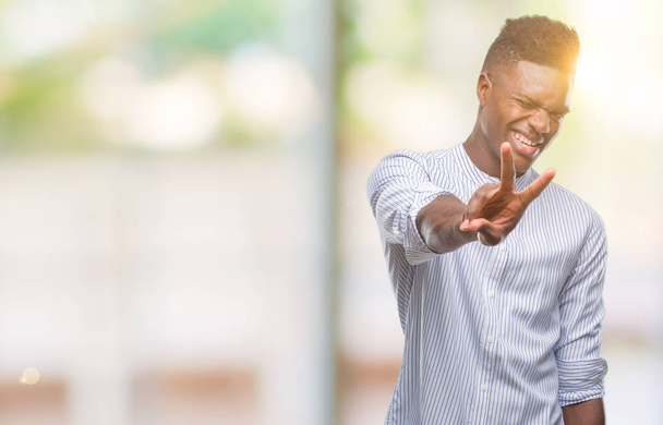 Jonge Afro-Amerikaanse man over geïsoleerde achtergrond glimlachend op zoek naar de camera vingers doen overwinning teken tonen. Nummer twee. - Foto, afbeelding
