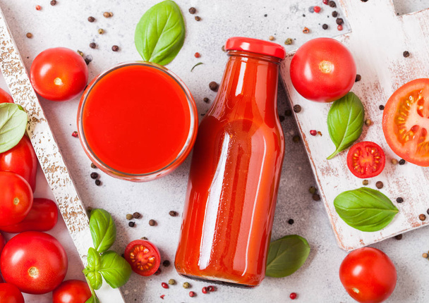 Bottle of fresh organic tomato juice with fresh raw tomatoes basil and pepper in box on stone background - Photo, Image