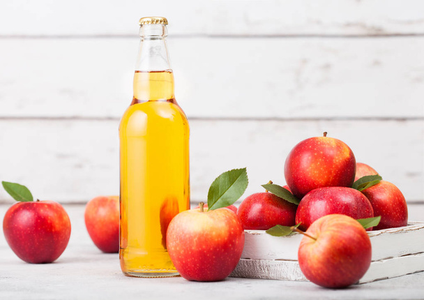 Bottle of homemade organic apple cider with fresh apples in box on wooden background, Glass with ice cubes - Zdjęcie, obraz