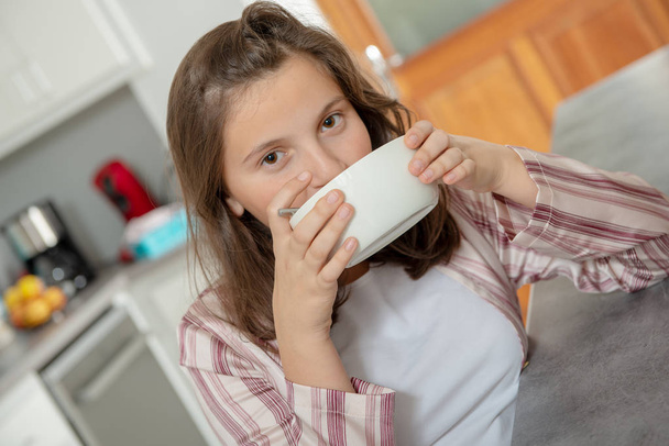 Утром девочка-подросток пьет кофе в миске
 - Фото, изображение