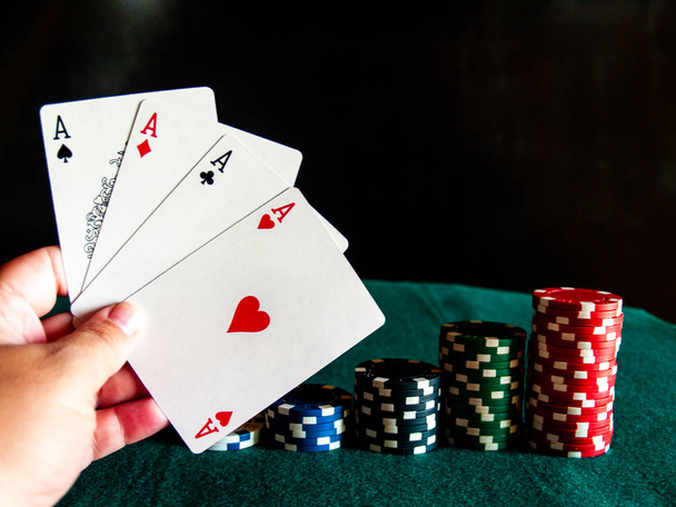 Člověk hrát poker s čtyři esa balíček v jeho rukou a poker žetonů různých barev na zelený mat - Fotografie, Obrázek