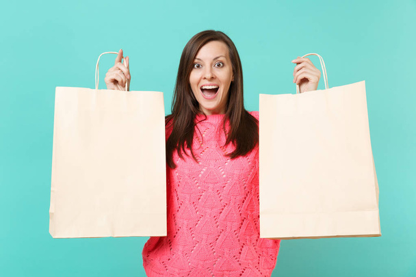 Aufgeregt überrascht junge Frau in gestricktem rosa Pullover hält in den Händen Einkaufstasche mit Schriftzug Verkauf isoliert auf blauem Wandhintergrund. Menschen Lebensstil Konzept. Attrappe Kopierraum - Foto, Bild