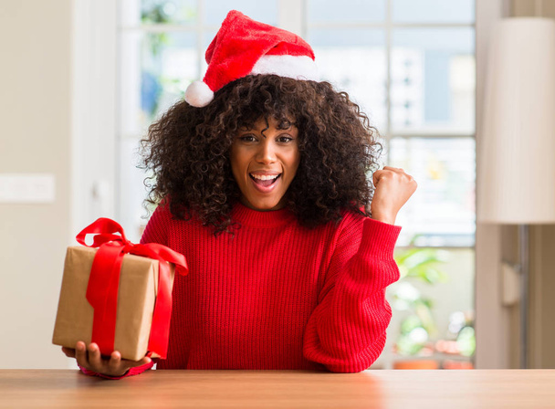 Афро-американських жінки, що тримає сьогодення капелюсі Різдво червоним кричати і гордий і святкування перемоги і успіх дуже схвильований, вітаючи емоцій - Фото, зображення