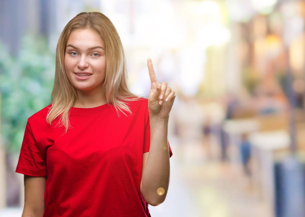 junge kaukasische Frau über isoliertem Hintergrund, die mit Finger Nummer eins zeigt und nach oben zeigt, während sie selbstbewusst und glücklich lächelt. - Foto, Bild