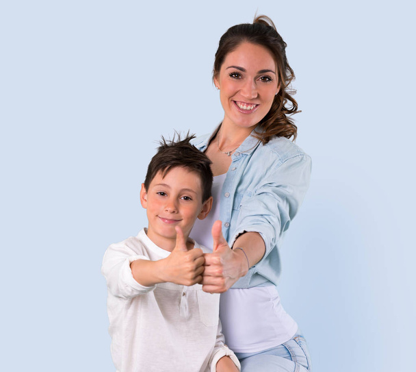 Matka a dcera dává palec nahoru gesto a usmívá se na modrém pozadí - Fotografie, Obrázek