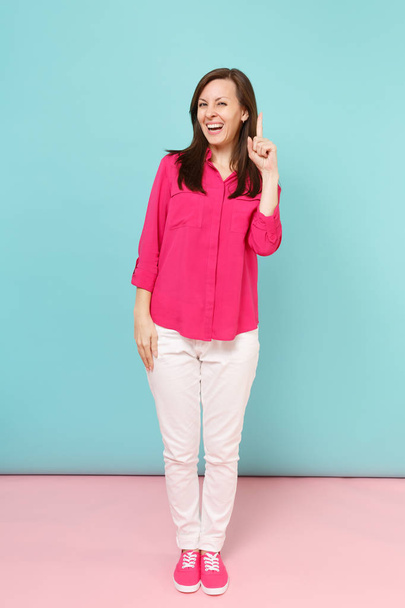 Retrato de larga duración de una joven y bonita mujer sonriente en blusa de camisa rosa, pantalones blancos posando aislados en un estudio de fondo de pared pastel azul rosado brillante. Concepto de estilo de vida. Simular espacio de copia
 - Foto, Imagen