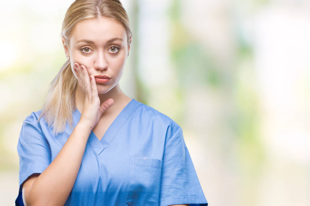Young blonde surgeon doctor woman wearing medical uniform over isolated background thinking looking tired and bored with depression problems with crossed arms. - Фото, зображення