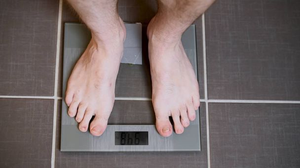 Pés masculinos em escamas de vidro, dieta masculina, peso corporal
 - Foto, Imagem