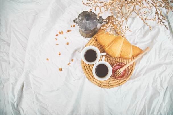 Guten Morgen. zwei Tassen Kaffee mit Croissant und Marmelade. Frühstück auf weißen Bettwäsche von oben. Ansicht von oben. flach lag. Kopierraum. Romantisches Frühstück. - Foto, Bild