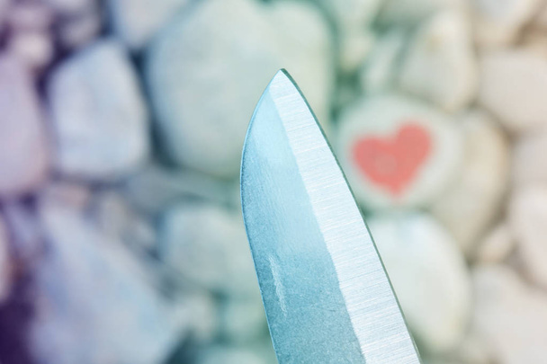 Couteau de coupe plongeant coeur rose peint avec du rouge à lèvres sur un morceau de pierre. Symbole de la fin de l'amour et de la séparation et du divorce de deux personnes
 - Photo, image