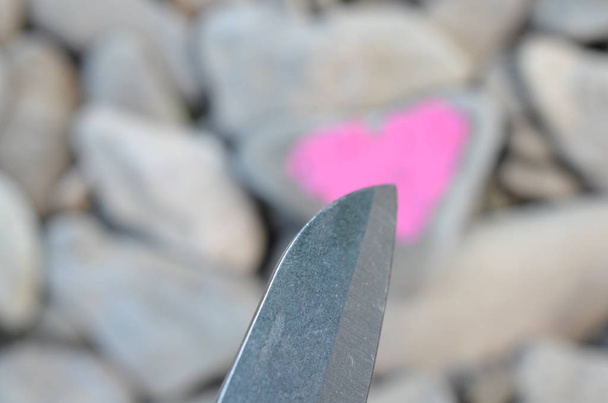 Couteau de coupe plongeant coeur rose peint avec du rouge à lèvres sur un morceau de pierre. Symbole de la fin de l'amour et de la séparation et du divorce de deux personnes
 - Photo, image
