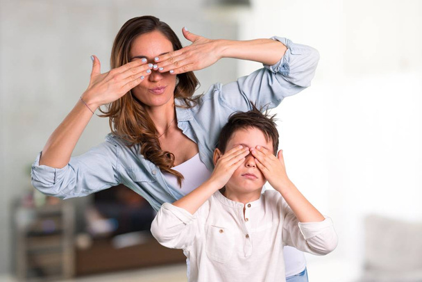 Mère et fille couvrant les yeux par les mains à l'intérieur de la maison
 - Photo, image