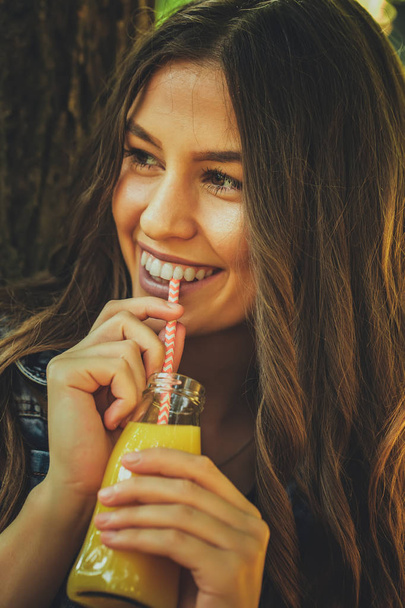 Portrait of beautiful happy smiling teenage girl while drinking juice - Photo, Image