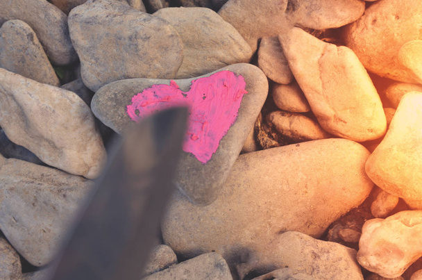 Coltello da taglio tuffo cuore rosa dipinto con rossetto su pietra. Simbolo della fine dell'amore e di due persone che si separano e divorziano
 - Foto, immagini