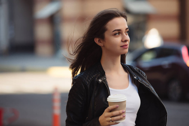 Beautiful woman holding paper coffee cup and enjoying a walk in the city - Foto, Imagem