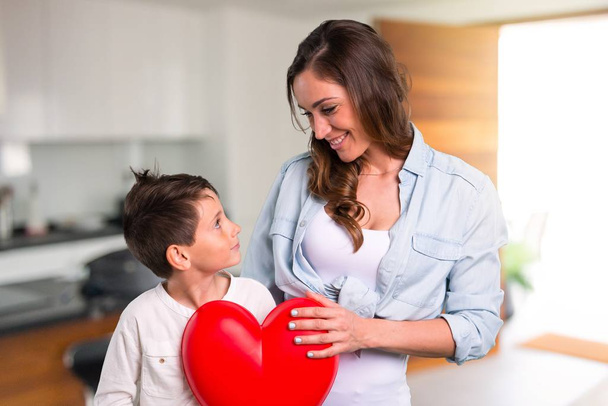 Мати і дочка тримають велику ікону серця іграшку всередині будинку
 - Фото, зображення