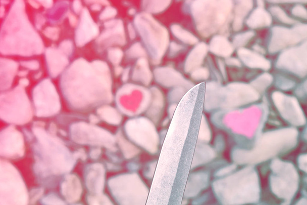 Ріжучий ніж для дайвінгу рожеве серце, пофарбоване помадою на шматок каменю. Символ кінця любові і двох людей розлучитися і розлучитися
 - Фото, зображення