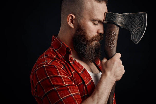 lumberjack. Confident bearded man attached to forehead axe - Fotó, kép