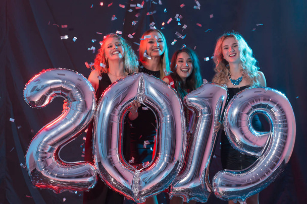 Концепция вечеринок, праздников и людей - Группа подруг, празднующих Новый год с большим символом 2019 года
 - Фото, изображение