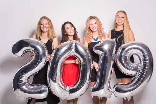 Zbliża się nowy 2019 roku. Grupa wesoły młodych kobiet, trzymając srebrny kolorowymi numerami partii. - Zdjęcie, obraz