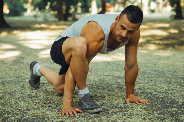 Young fitness man runner stretching legs before run - Photo, Image
