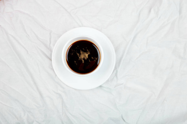 One Cup of coffee on white bed. Concept good morning. Lifestyle. Relax. Vacation. Copy space. Top view. - Фото, изображение