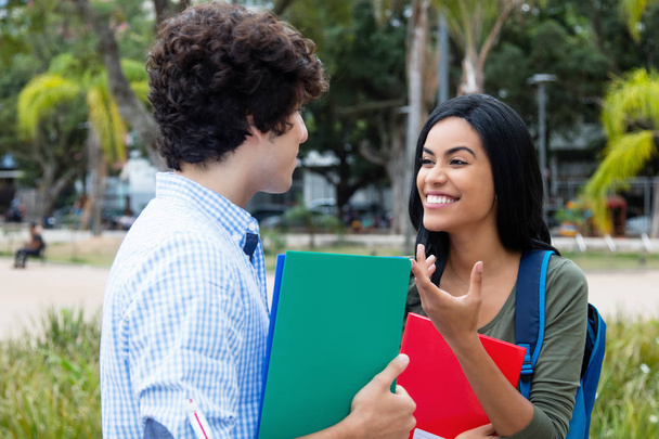 Indian female student talking with caucasian male student outdoor on campus of university - Foto, immagini