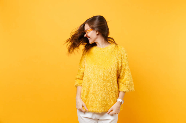 De jonge vrouw gelach in trui, hart oranje bril gek rond in studio met haar geïsoleerd op heldere gele achtergrond wapperen. Mensen oprechte emoties, lifestyle concept. Gebied van de reclame - Foto, afbeelding