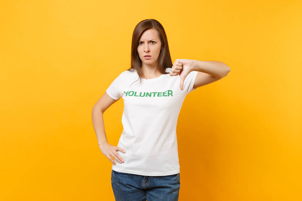 Portret smutny, zdenerwowany szoku młodej kobiety w biały t-shirt z pisemnej napis zielony tytuł wolontariusza na białym tle na żółtym tle. Dobrowolne bezpłatnej pomocy pomoc, miłość łaskę pracy koncepcja - Zdjęcie, obraz