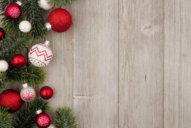 Bordo laterale di Natale di bagattelle rosse e bianche con rami d'albero su uno sfondo di legno grigio rustico
 - Foto, immagini