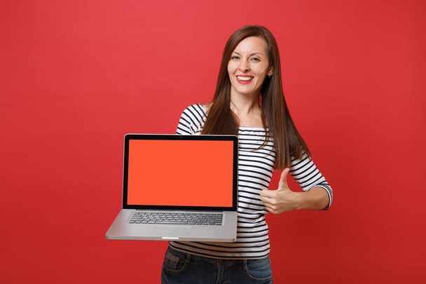 Красива молода жінка, що показує великий палець, тримає комп'ютер для ноутбуків з порожнім чорним порожнім екраном ізольовано на яскраво-червоному тлі стіни. Люди щирі емоції, концепція способу життя. Збільшити простір для копіювання
 - Фото, зображення