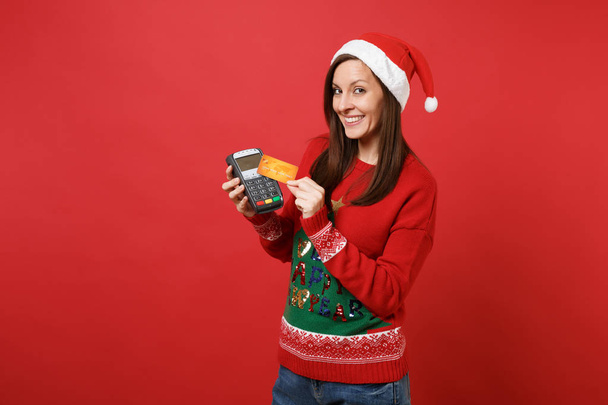 Houkutteleva Santa tyttö tilalla langaton moderni pankki maksupäätteen käsitellä ja hankkia luottokorttimaksuja, kortti eristetty punaisella taustalla. Hyvää uutta vuotta 2019 juhla loma juhlakonsepti
 - Valokuva, kuva