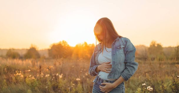 Fiatal terhes nő gazdaság ultrahangos fénykép, a naplemente, és átfogó a hasát. 4 hónapos terhesség. Szülési koncepció. Tónusú fénykép - Fotó, kép
