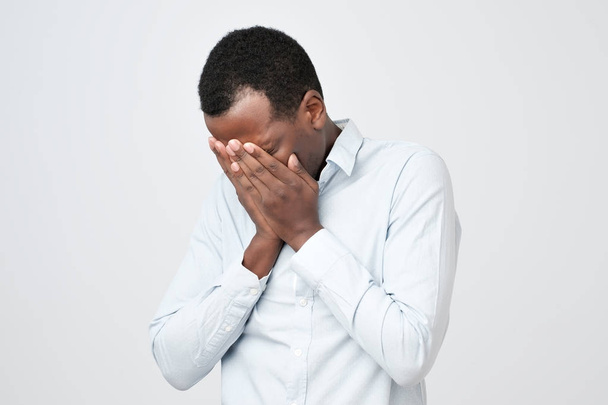 Взрослый африканский мужчина с грустным лицом, закрывающим лицо руками во время плача
. - Фото, изображение