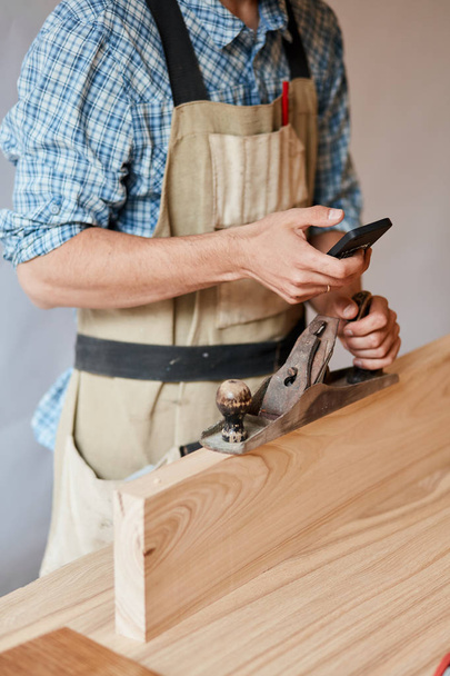 carpenter working with wood using plane against white wall in studio. - Foto, Imagem