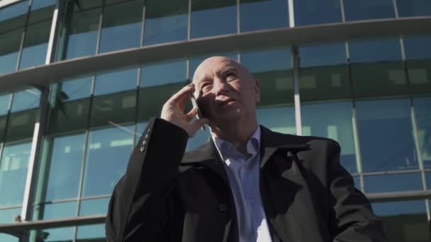 Adult man talking on the phone on the background of the business center - Filmagem, Vídeo