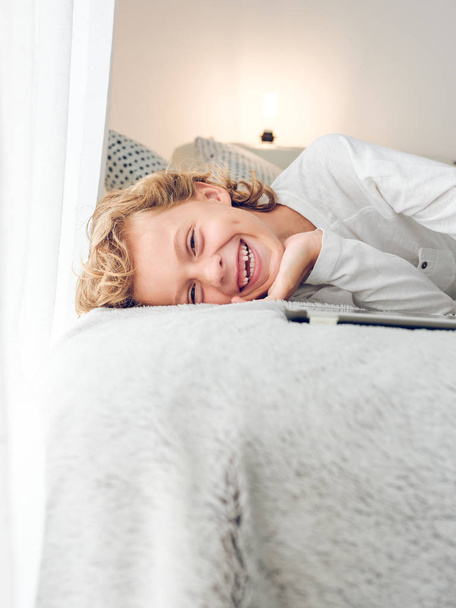 Söpö nauraa poika makaa sohvalla digitaalinen tabletti
 - Valokuva, kuva