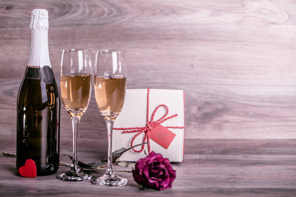 San Valentino. Champagne, bicchieri di vino, rosa e regalo in una scatola. Appuntamento, Compleanno. Concetto: felicità, vacanza
 - Foto, immagini