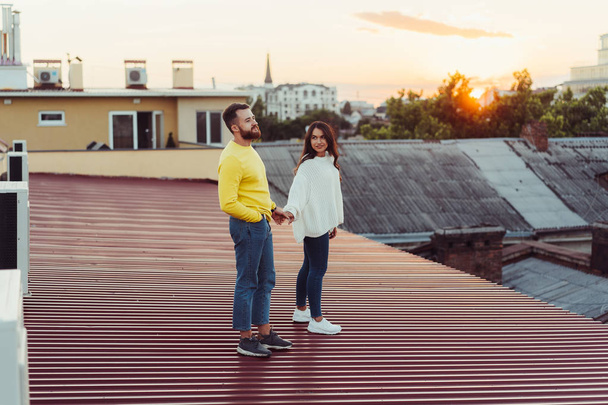 Любляча молода пара стоїть на даху будинку
. - Фото, зображення