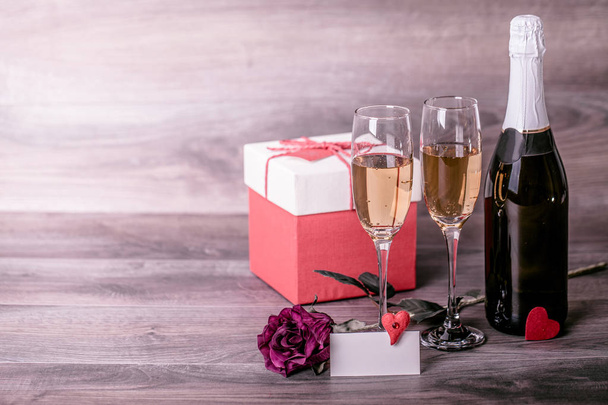 San Valentino. Champagne, bicchieri di vino, rosa, regalo in una scatola e messaggio d'amore. Appuntamento, Compleanno. Concetto: felicità, vacanza
 - Foto, immagini