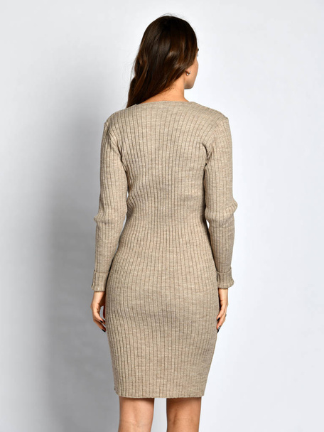 Young beautiful woman posing in new gray fashion winter knitted dress back side from behind - Zdjęcie, obraz