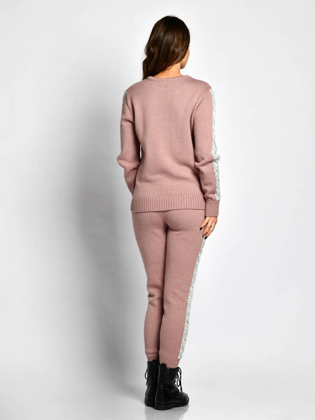 Young beautiful woman posing in new light pink fashion winter knitted suit full body back side from behind  - Foto, Imagem