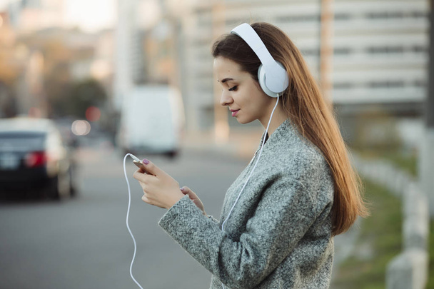 Woman listening to music with headphones in city - Foto, afbeelding