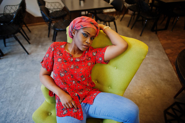 Stylish african woman in red shirt and hat posed indoor cafe. - Φωτογραφία, εικόνα