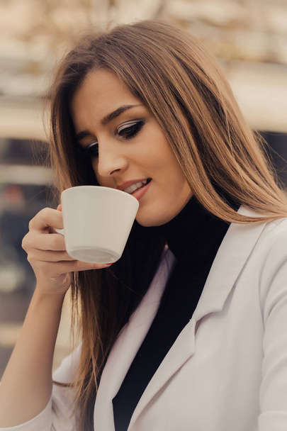 Close up portrait of young beautiful happy woman sitting in a cafe outdoor drinking coffee - Photo, Image